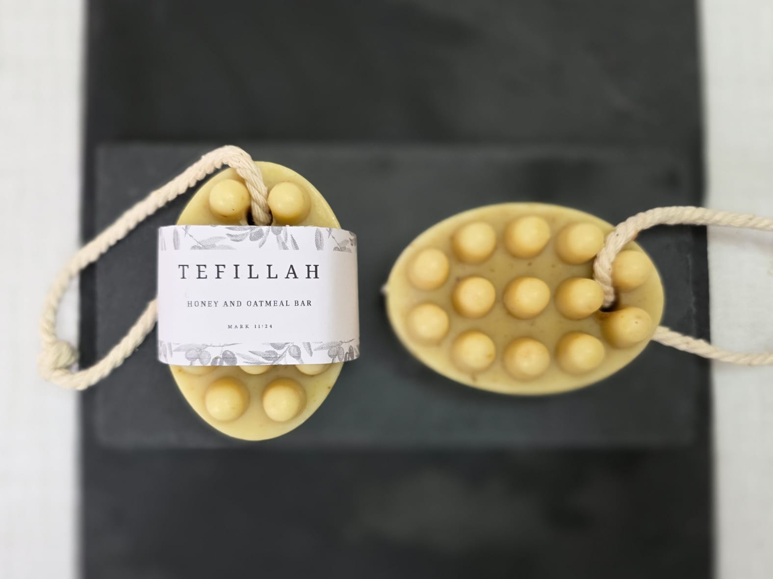 Close-up of Tefillah honey and oatmeal soap on a rope showing natural oatmeal texture, made with colloidal oatmeal, honey and shea butter